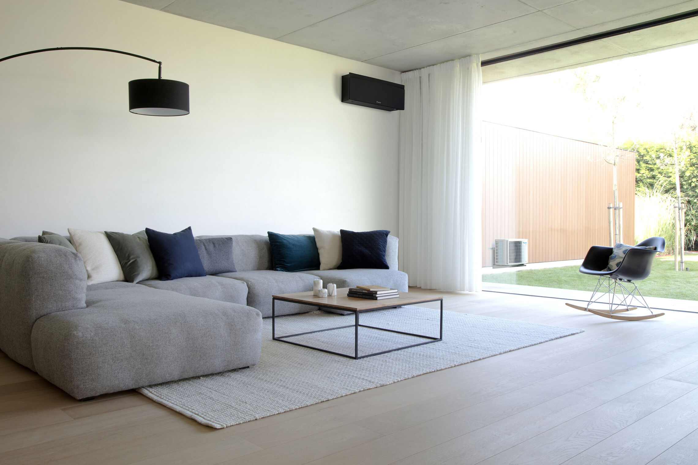 Daikin Emura 3 im modernen Wohnzimmer über einem hellen Sofa