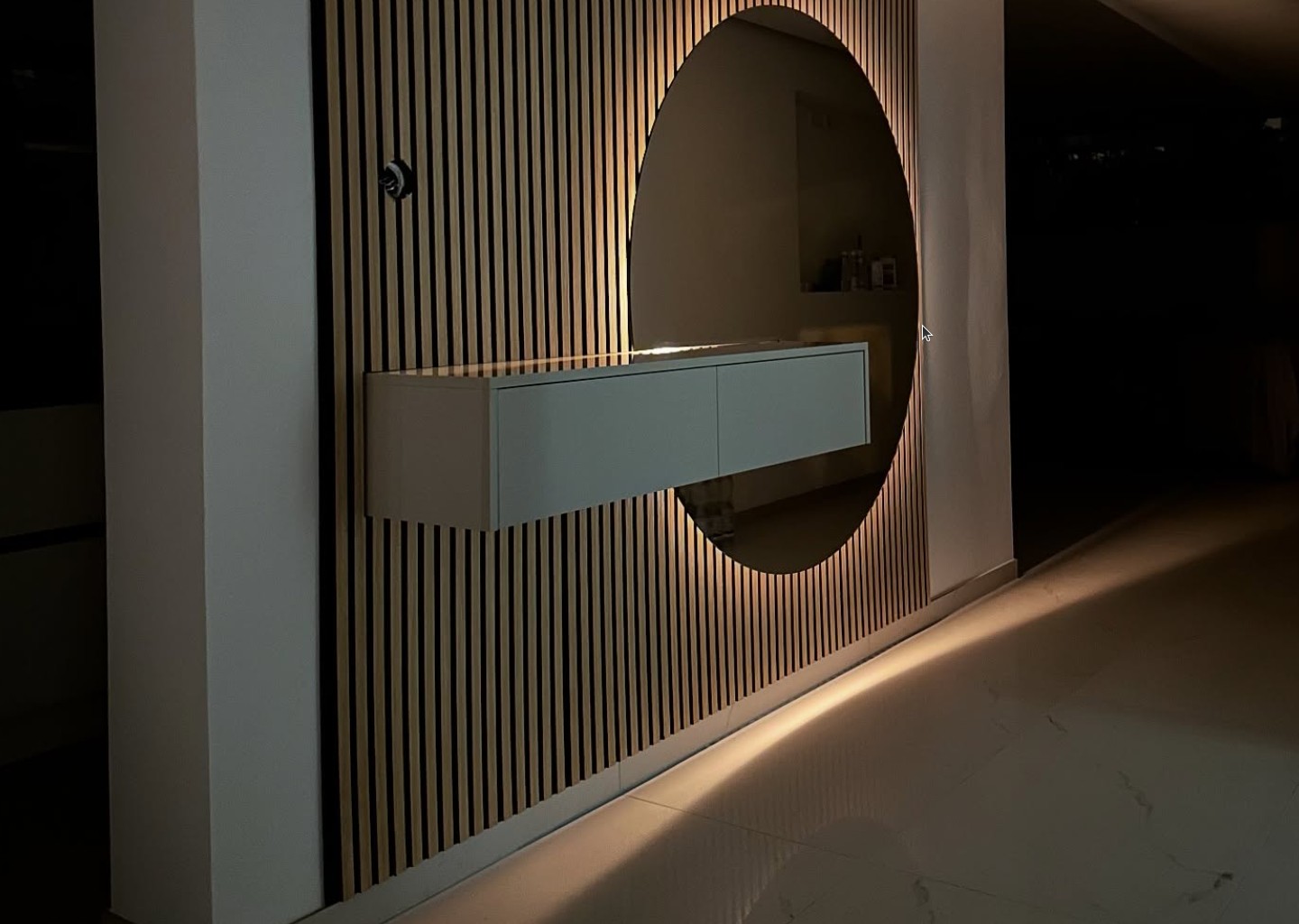 Flur bei Nacht mit Lamellenwand, rundem Spiegel und schwebendem Sideboard